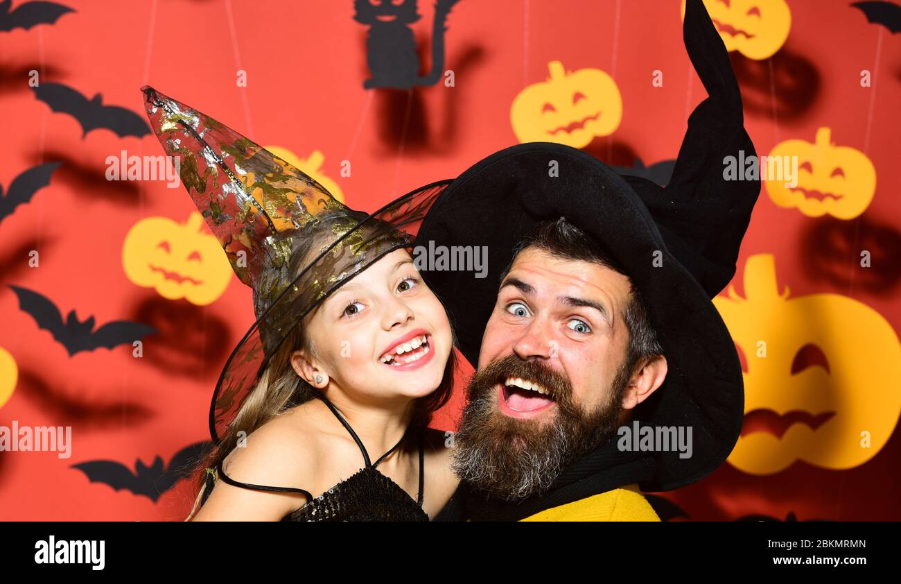 Chica y barbudo hombre con caras sorprendidas sobre fondo rojo con  decoración. Padre e hija en disfraces de Halloween. Fiesta de Halloween y  concepto de celebración. Mago y pequeña bruja en sombreros