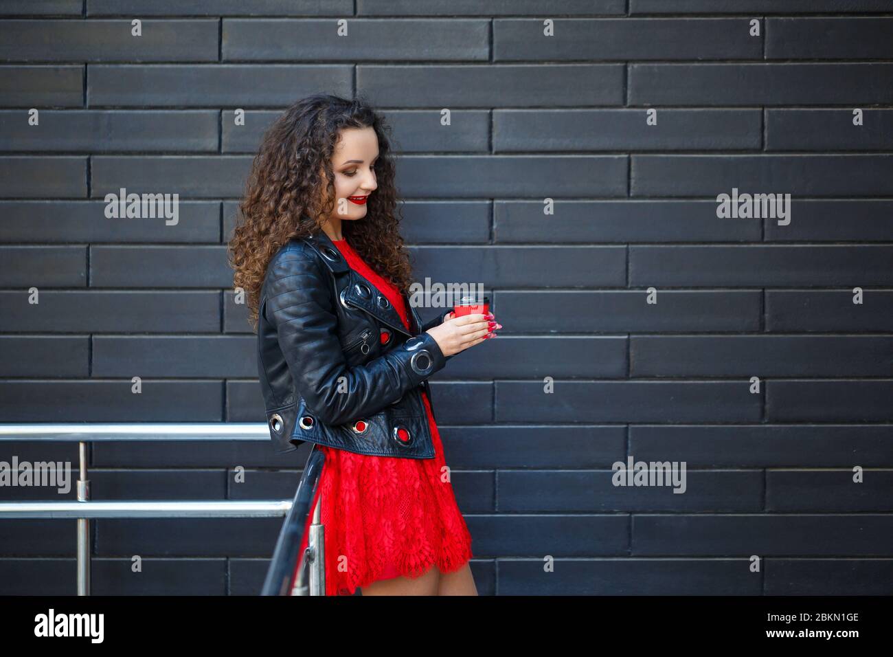 Una niña con un vestido rojo y una chaqueta negra bebe café de una taza de  papel rojo Fotografía de stock - Alamy