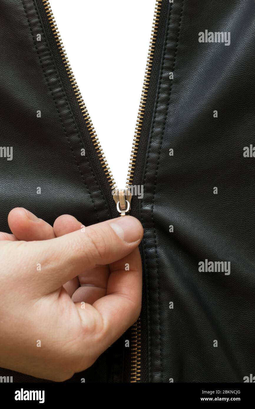 la mano de un hombre descomprime una cremallera metálica en una chaqueta de cuero negro, sobre un fondo aislado Foto de stock