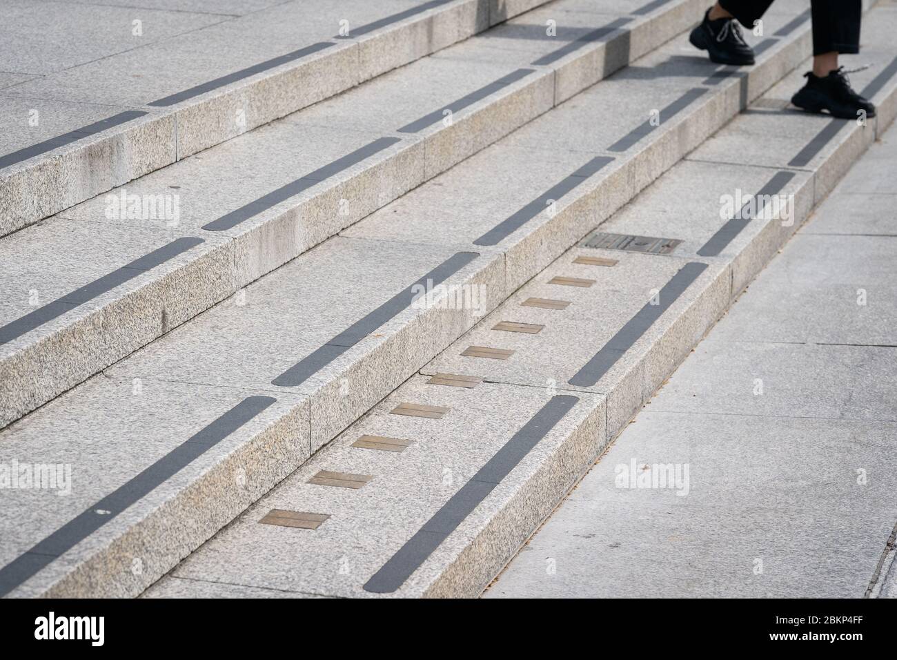 Una persona pasa los marcadores de medición imperiales incorporados en los escalones que conducen a la Galería Nacional de Retratos en Trafalgar Square en Londres mientras el Reino Unido continúa en el cierre para ayudar a frenar la propagación del coronavirus. Foto de stock