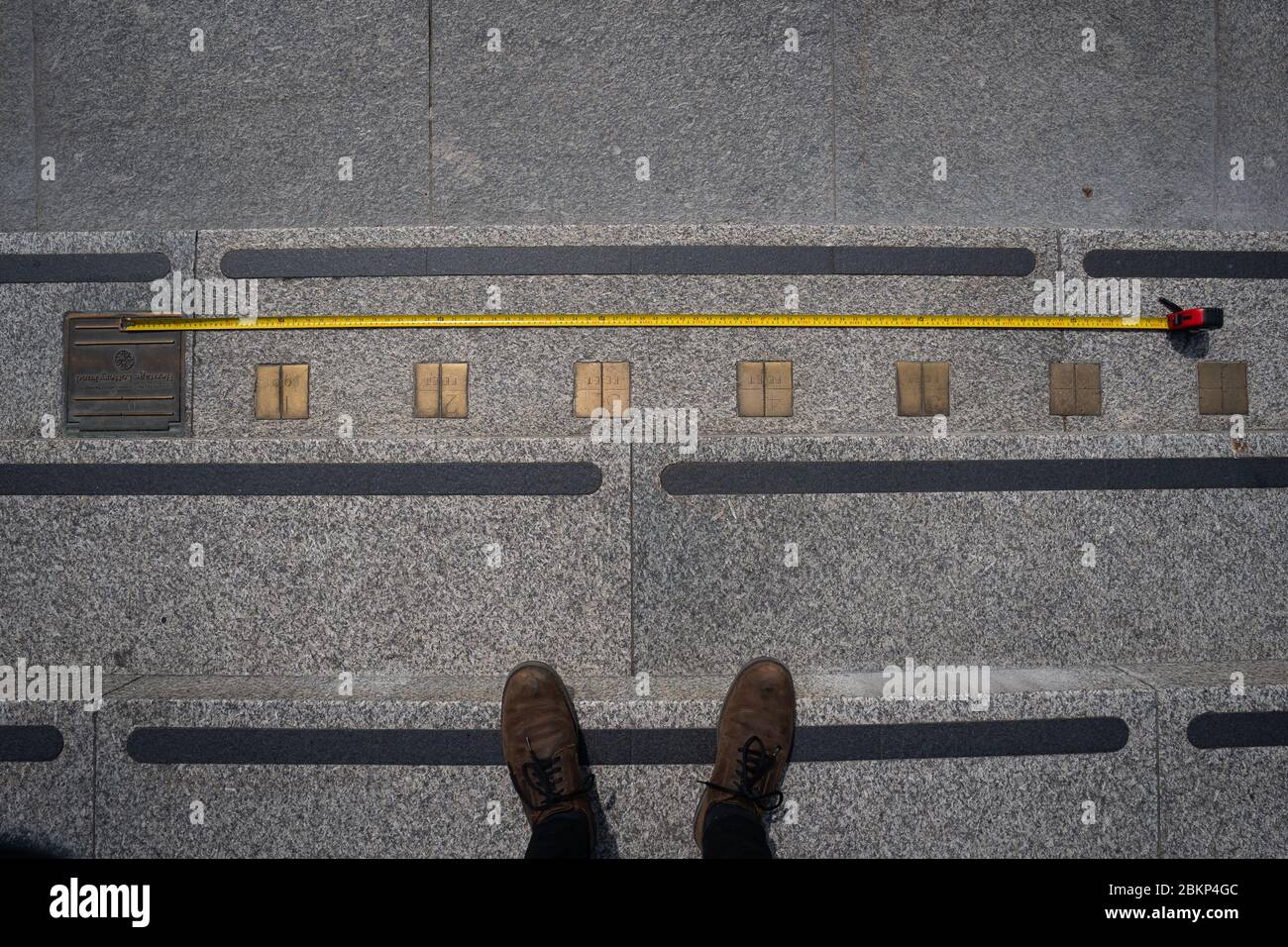 Se coloca una cinta métrica contra los marcadores de medición imperiales incorporados en los escalones que conducen a la Galería Nacional de Retratos en Trafalgar Square en Londres, mientras el Reino Unido continúa en bloqueo para ayudar a frenar la propagación del coronavirus. Foto de stock