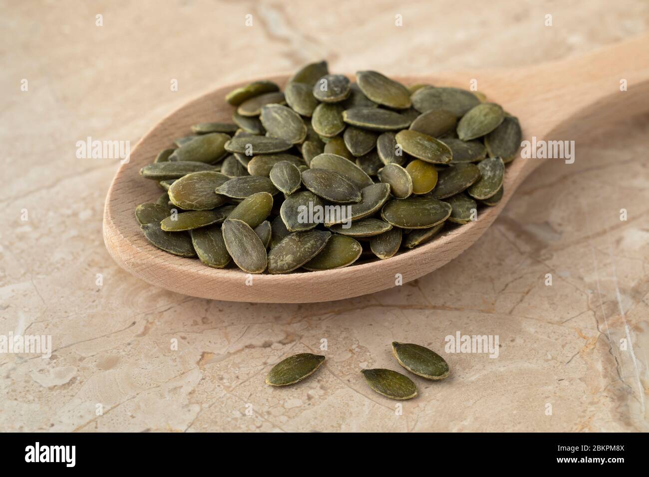 Cuchara de madera con semilla de calabaza seca como ingrediente Foto de stock