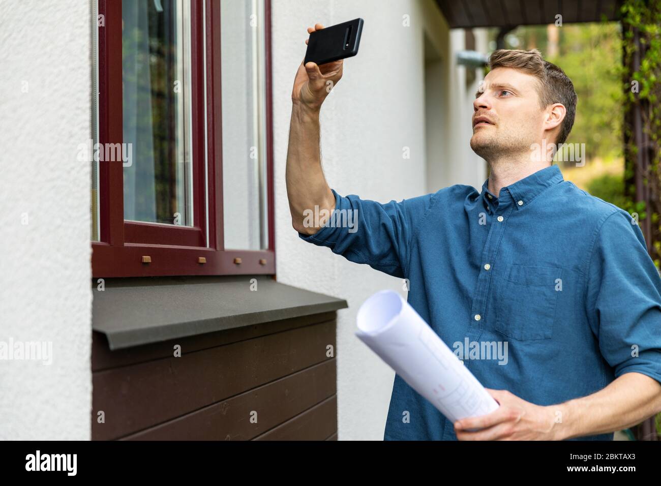 tasador de bienes raíces tomando fotos de la propiedad con el teléfono Foto de stock