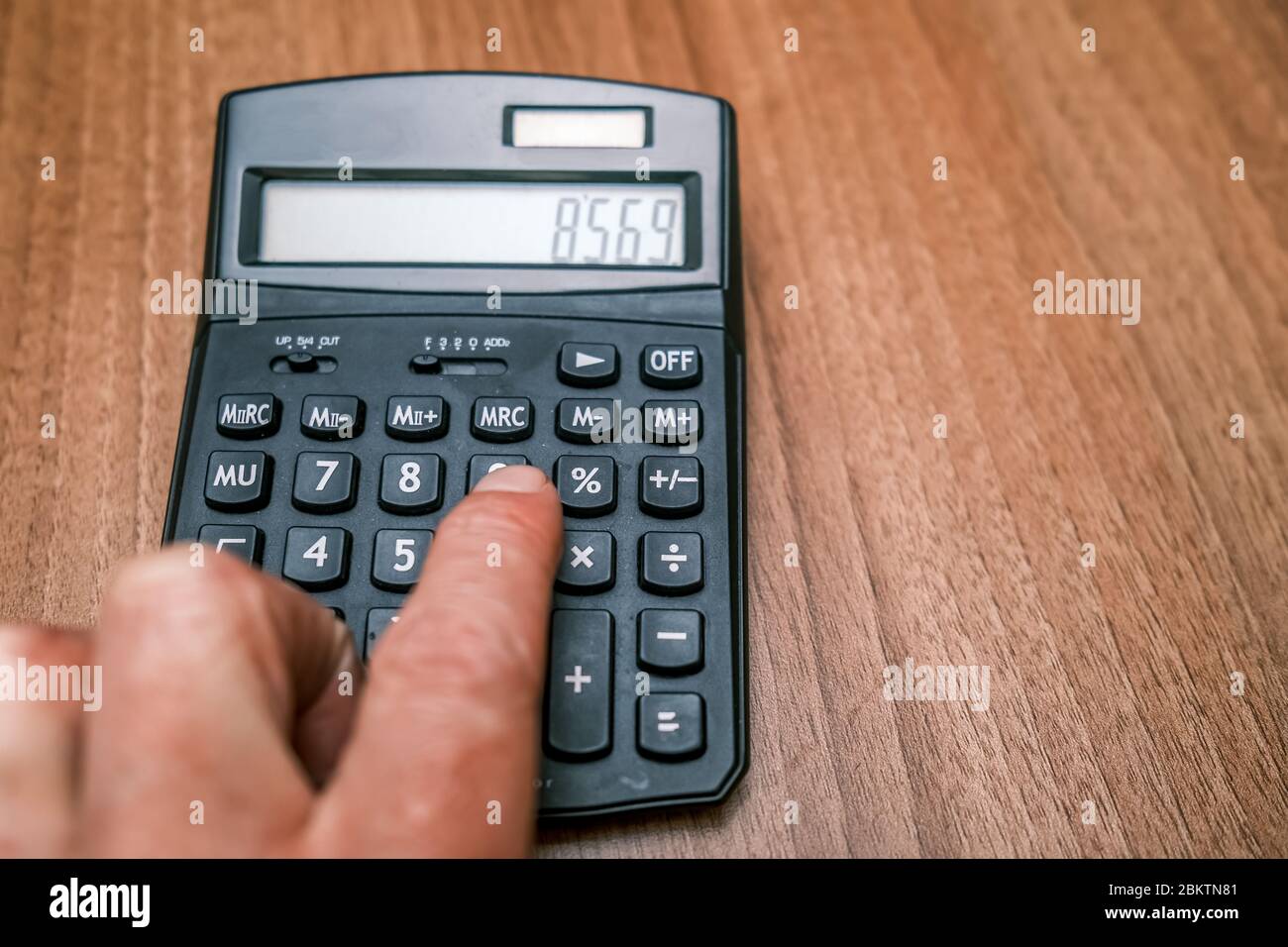 4 primer plano de la mano humana con una calculadora negra sobre un  escritorio de oficina de madera Fotografía de stock - Alamy