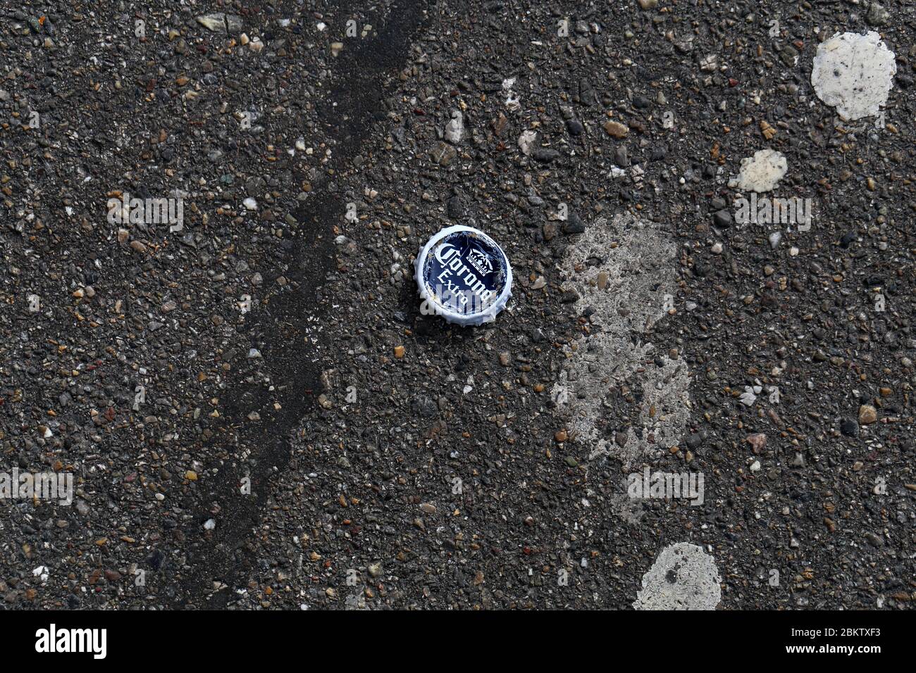 Tapa de botella de cerveza Corona en una carretera asfaltada, Zúrich, Suiza, marzo de 2020. Fotografiado desde arriba. Foto de stock