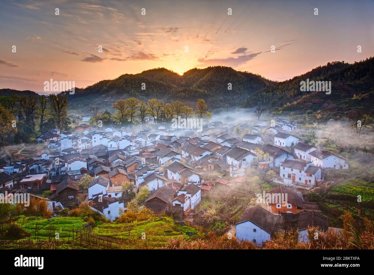 Amanecer sobre un pueblo de montaña cubierto por la niebla Foto de stock