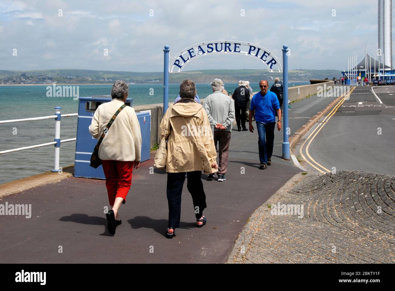 Grupos de ancianos que entran y salen del Pleasure Pier, Weymouth, Dorset, Inglaterra Foto de stock