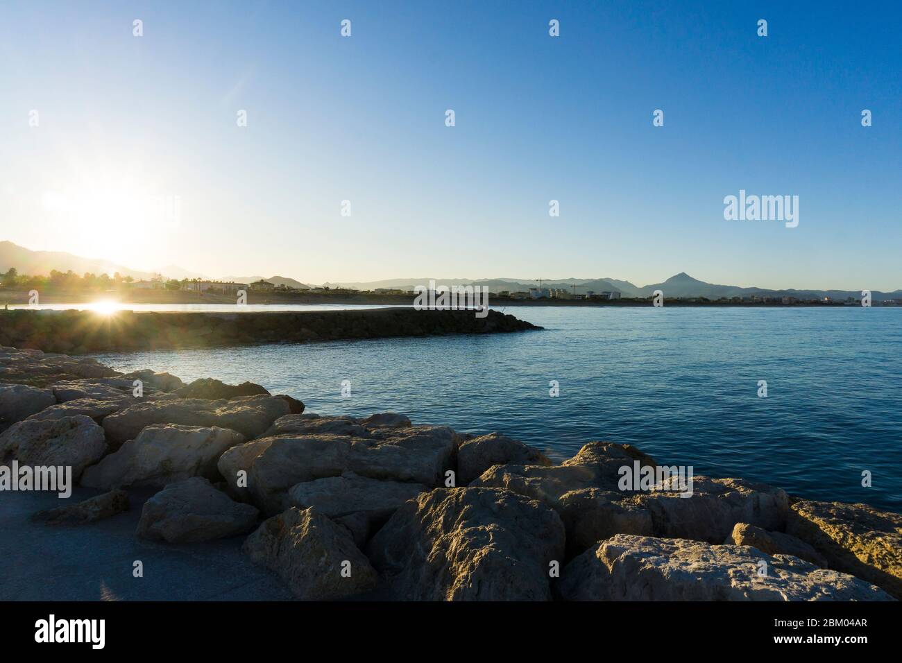 Puesta de sol sobre las montañas y el mar desde la muralla del puerto de  Oliva, región de Valencia, España Fotografía de stock - Alamy
