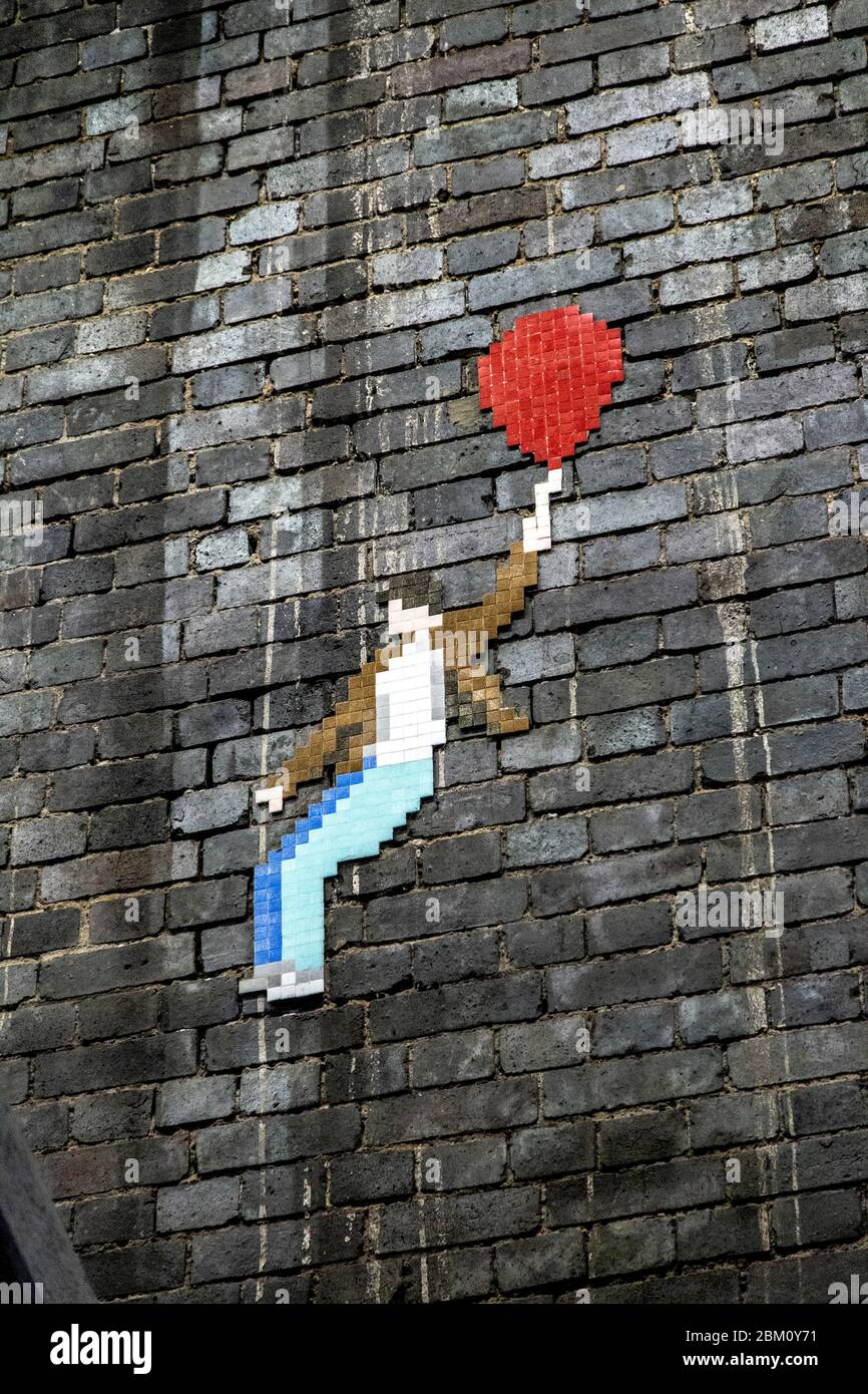 Hombre con dibujos en píxeles de globo rojo en el camino del Támesis bajo el puente del ferrocarril Blackfriars, Londres, Reino Unido Foto de stock