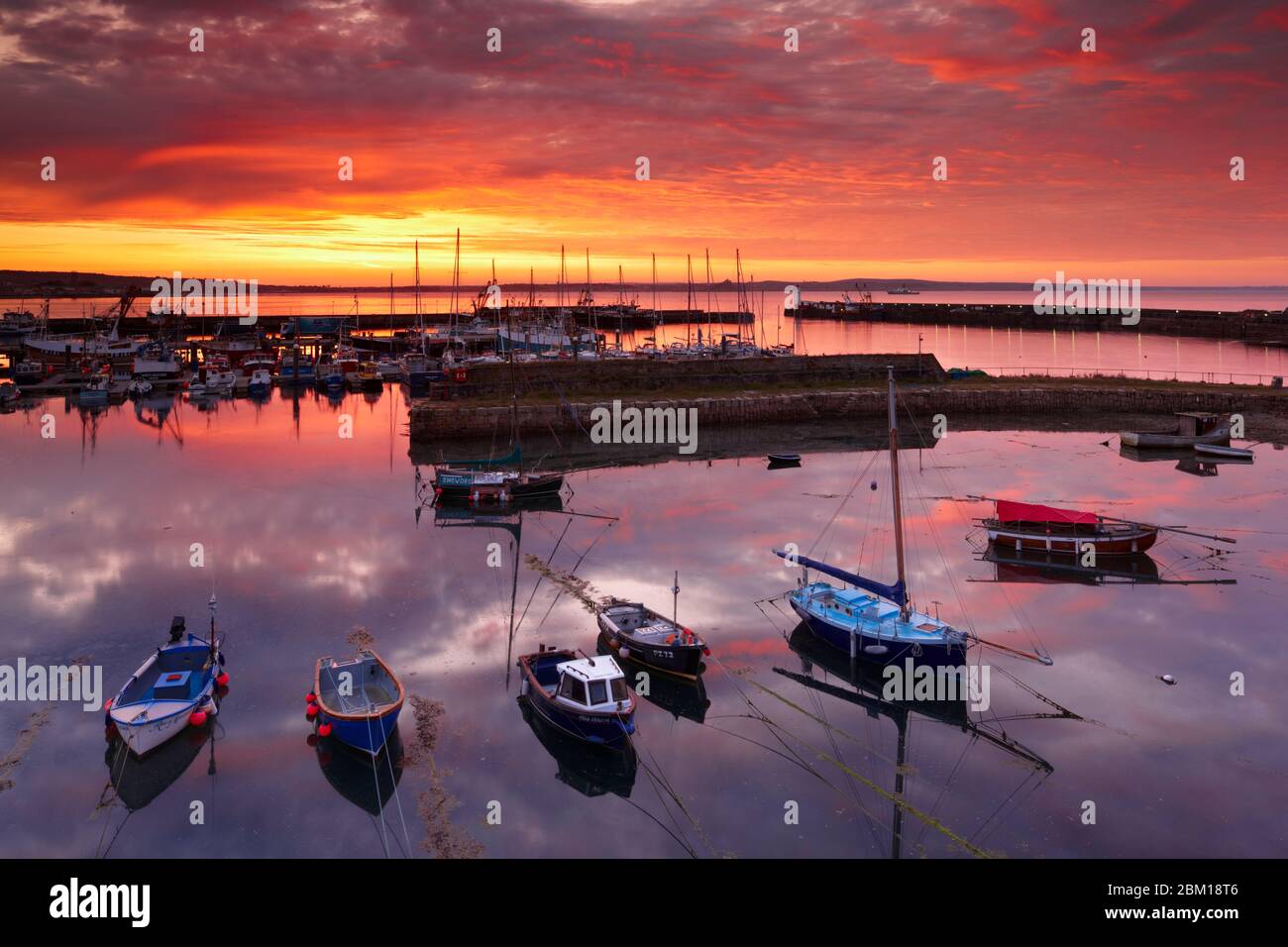 Un colorido amanecer sobre la Bahía de Montts y el Puerto Newlyn Foto de stock