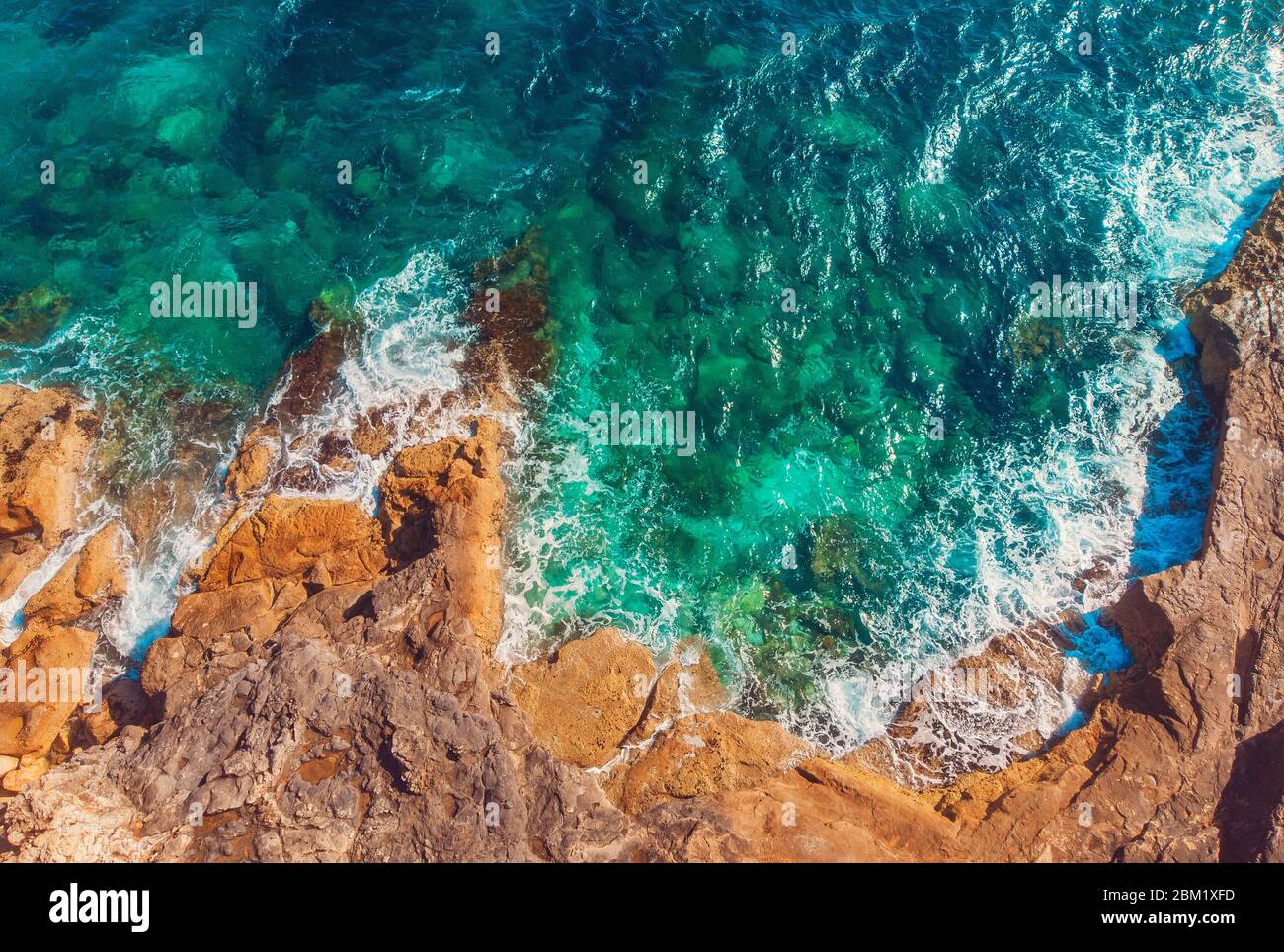 El agua clara de Azure llega a la costa rocosa de la playa de coral. Vista superior aérea Foto de stock