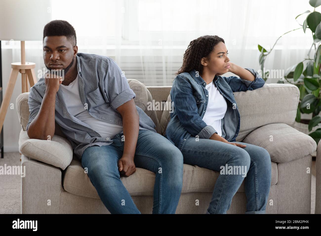 Los cónyuges negros sentados se ofendieron unos a otros después de discutir en el hogar Foto de stock