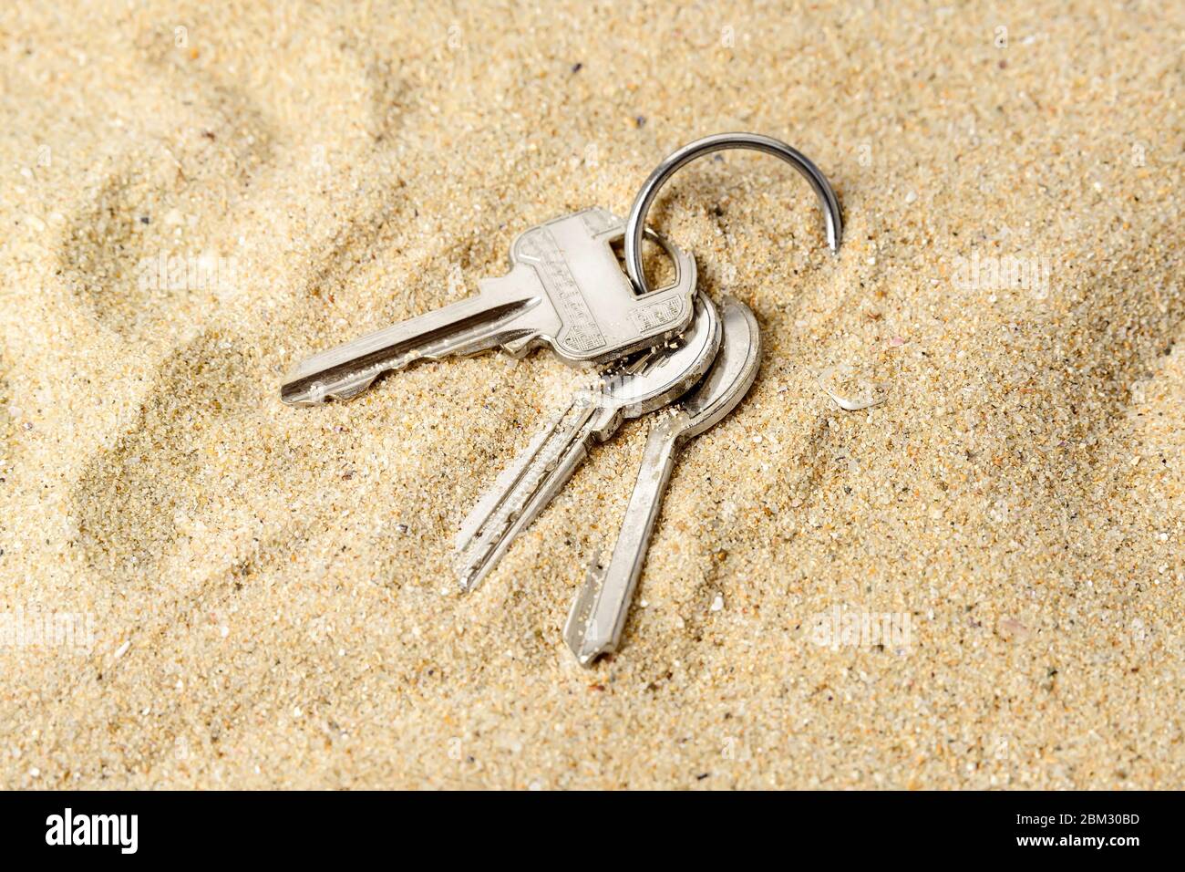 Anillo con tres llaves casa sobre una arena de mar. Olvídese o las llaves de la casa mientras se relaja en la playa. Soltar accidentalmente las teclas. un montón