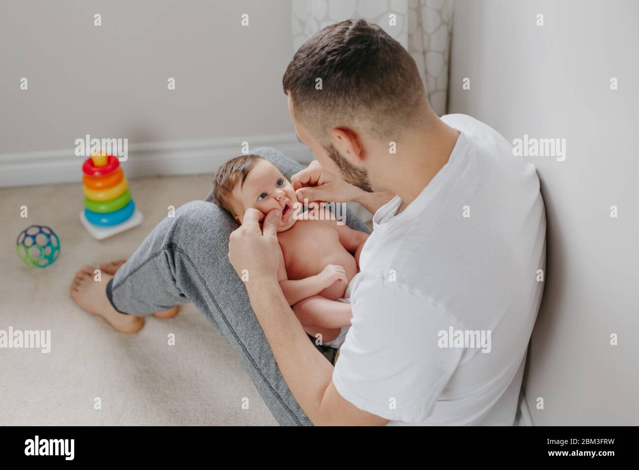 Feliz Padre Caucasico Sosteniendo Al Bebe Recien Nacido En Las Rodillas Padre Hombre Abrazando A Hijo De Hija Mecedora Autentico Estilo De Vida En El Momento Franco Orgulloso Y Fotografia De Stock