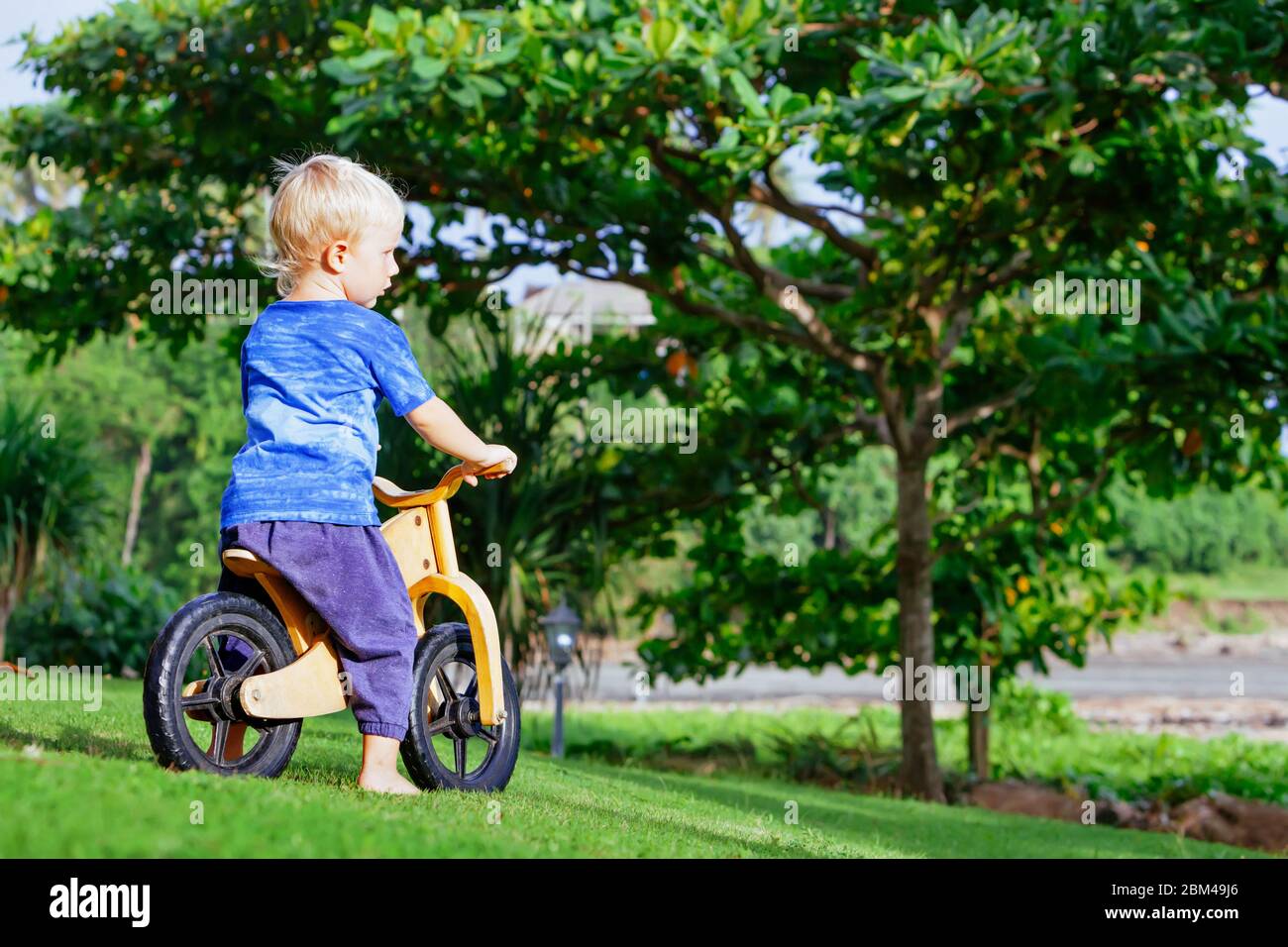 2 - 3 años alegre niño montando una bicicleta de equilibrio de madera ( bicicleta de carrera). Feliz
