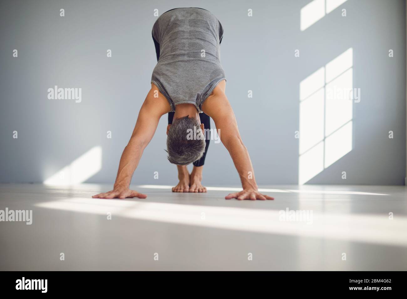 Ángulo bajo de hombre descalzo irreconocible en el enfoque de ropa deportiva  y haciendo ejercicio de yoga de perro orientado hacia abajo mientras  entrena solo en casa Fotografía de stock - Alamy
