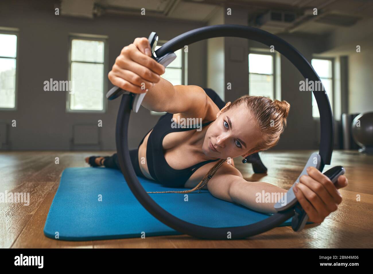 Joven modelo de fitness mujer atleta en sportswear haciendo ejercicios de estiramiento con expansor de caucho. Culturismo estilo de vida saludable concepto imagen Foto de stock
