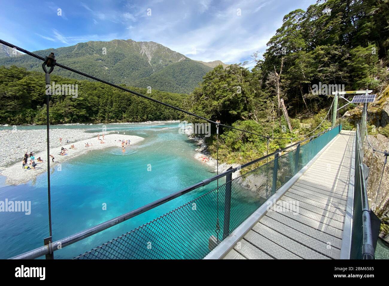 Piscinas azules claras y turquesa y puente colgante en el río Makarora en el Parque Nacional Mount Aspiring, Nueva Zelanda Foto de stock