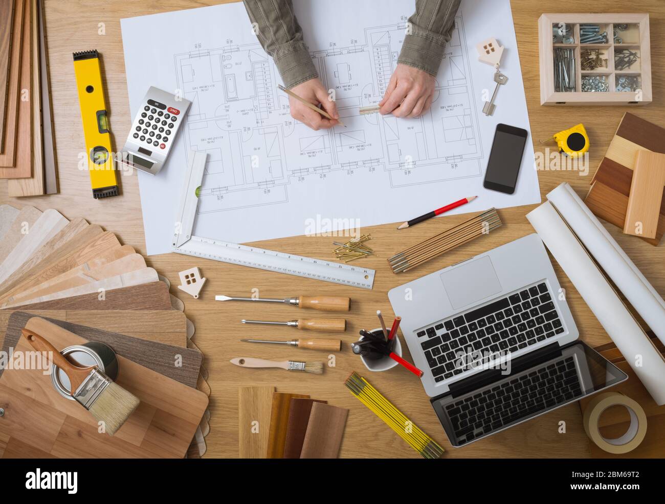 Construcción ingeniero y arquitecto's desk con proyectos de vivienda, ordenador portátil, herramientas y madera vista superior, muestras de dibujo manos macho Foto de stock