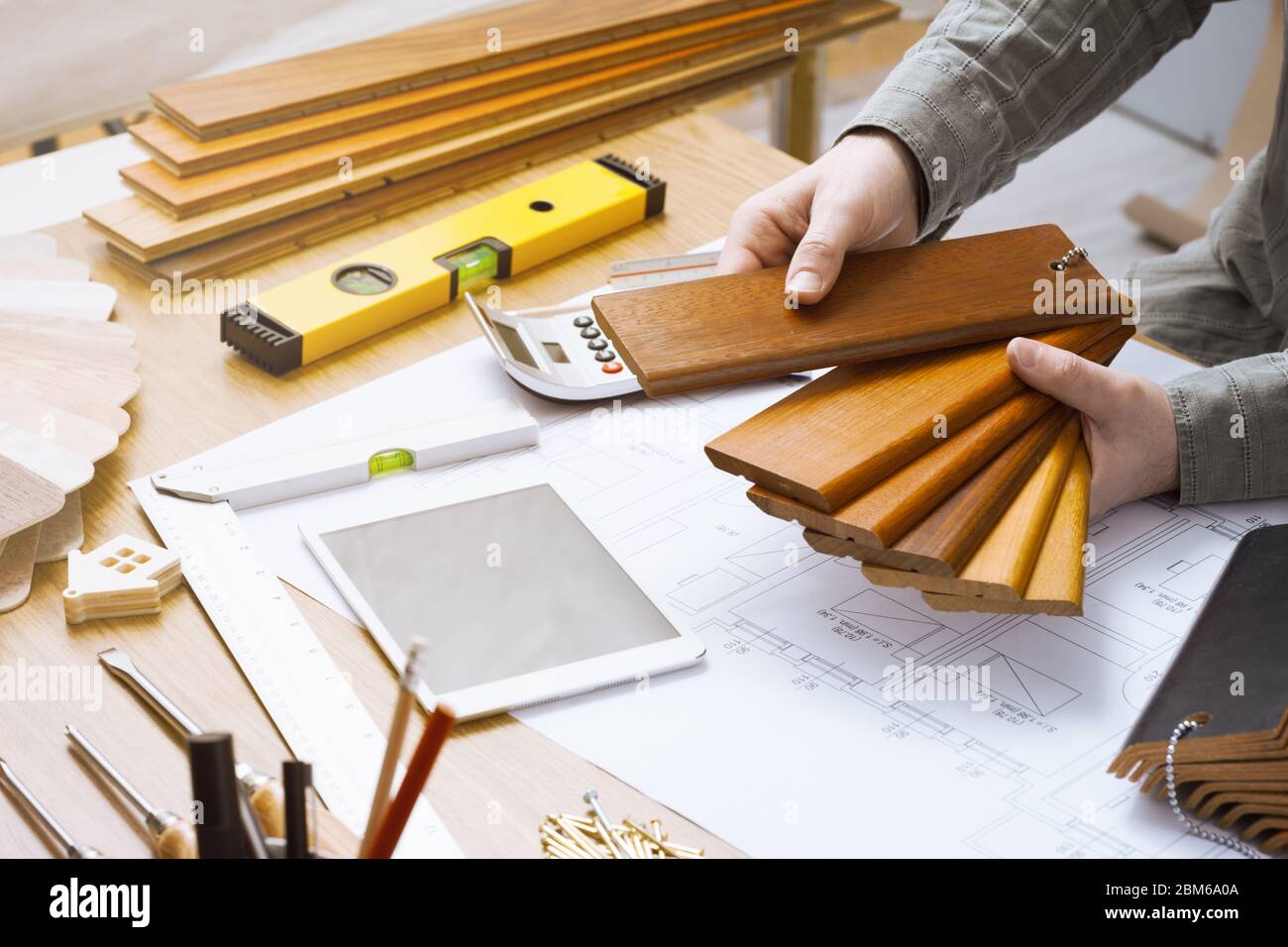 Diseñador de interiores profesional que sostiene relojes de madera para baseboard y rodapiés, manos cerca trabajando en el escritorio Foto de stock