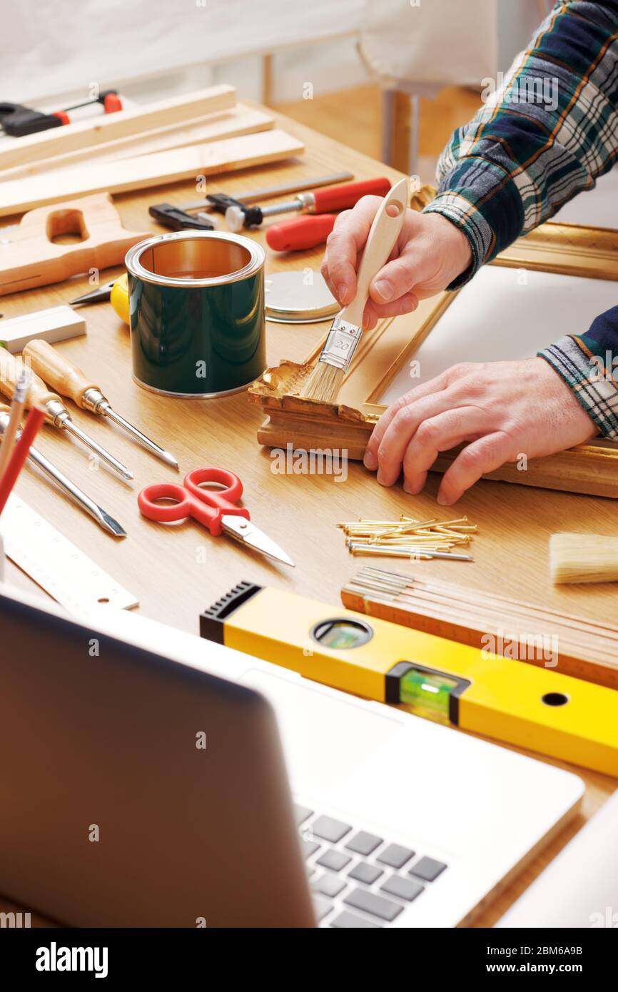 Decorador barnizar un marco de madera manos cerca con herramientas de bricolaje, hobby y concepto de artesanía Foto de stock