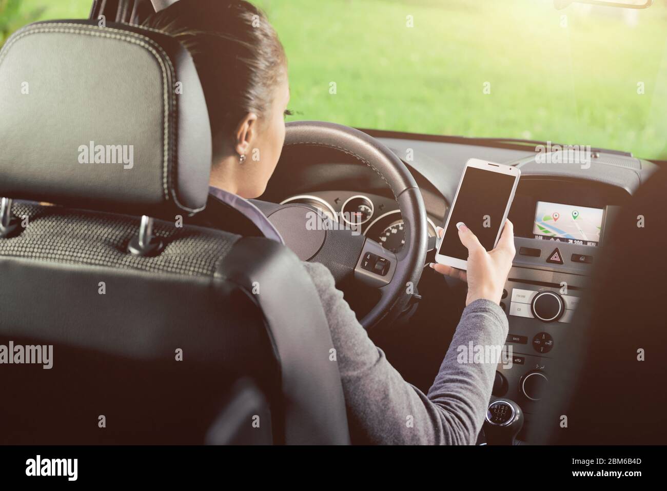 Joven conductor mediante un smartphone con pantalla táctil y la navegación GPS en el coche. Foto de stock