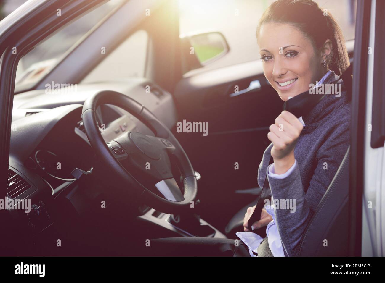 Atractiva mujer joven sentada en el asiento del coche y abrocharse el cinturón de seguridad, seguridad de los coches concepto. Foto de stock