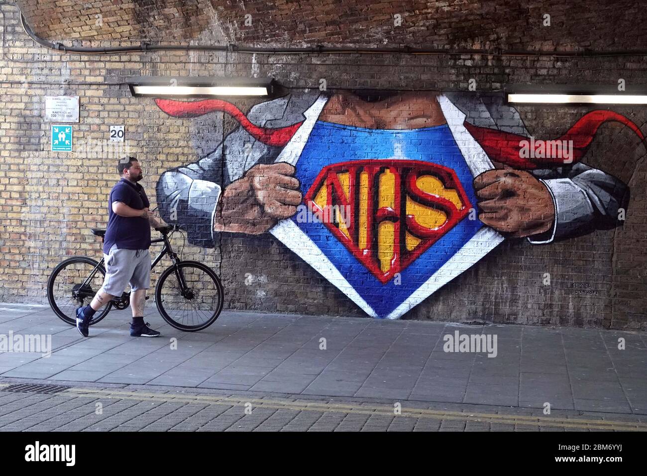 7.5.20 NHS Superman mural en Waterloo Londres hombre grande con bicicleta  camina pasado la foto por Pixel8000 Ltd Fotografía de stock - Alamy