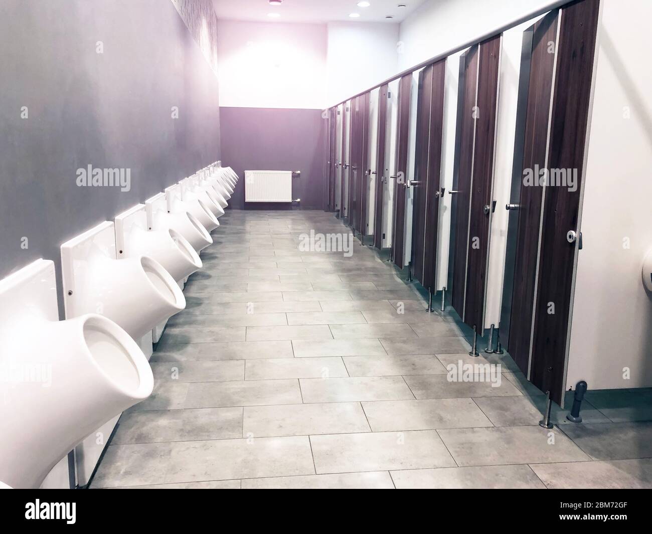 Baño público con puertas y urinarios en fila Fotografía de stock - Alamy