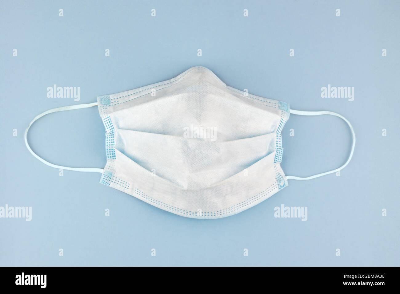 máscara de protección quirúrgica contra virus, como el coronavirus, sobre fondo azul pálido Foto de stock