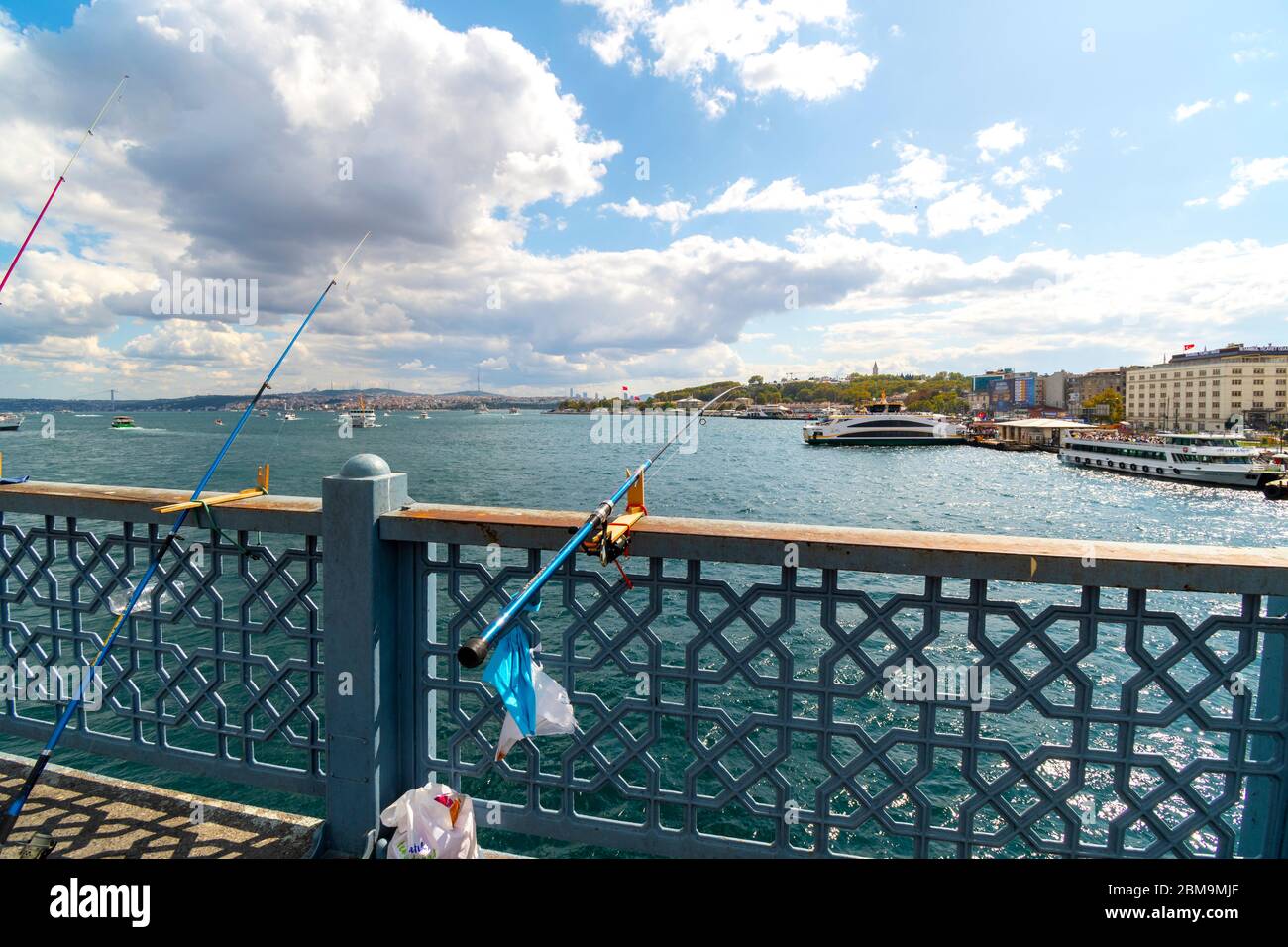 Las cañas de pescar y la línea sobresalen sobre el río Bósforo desde el puente de Gálata mientras los barcos de crucero atracan cerca en Estambul, Turquía Foto de stock