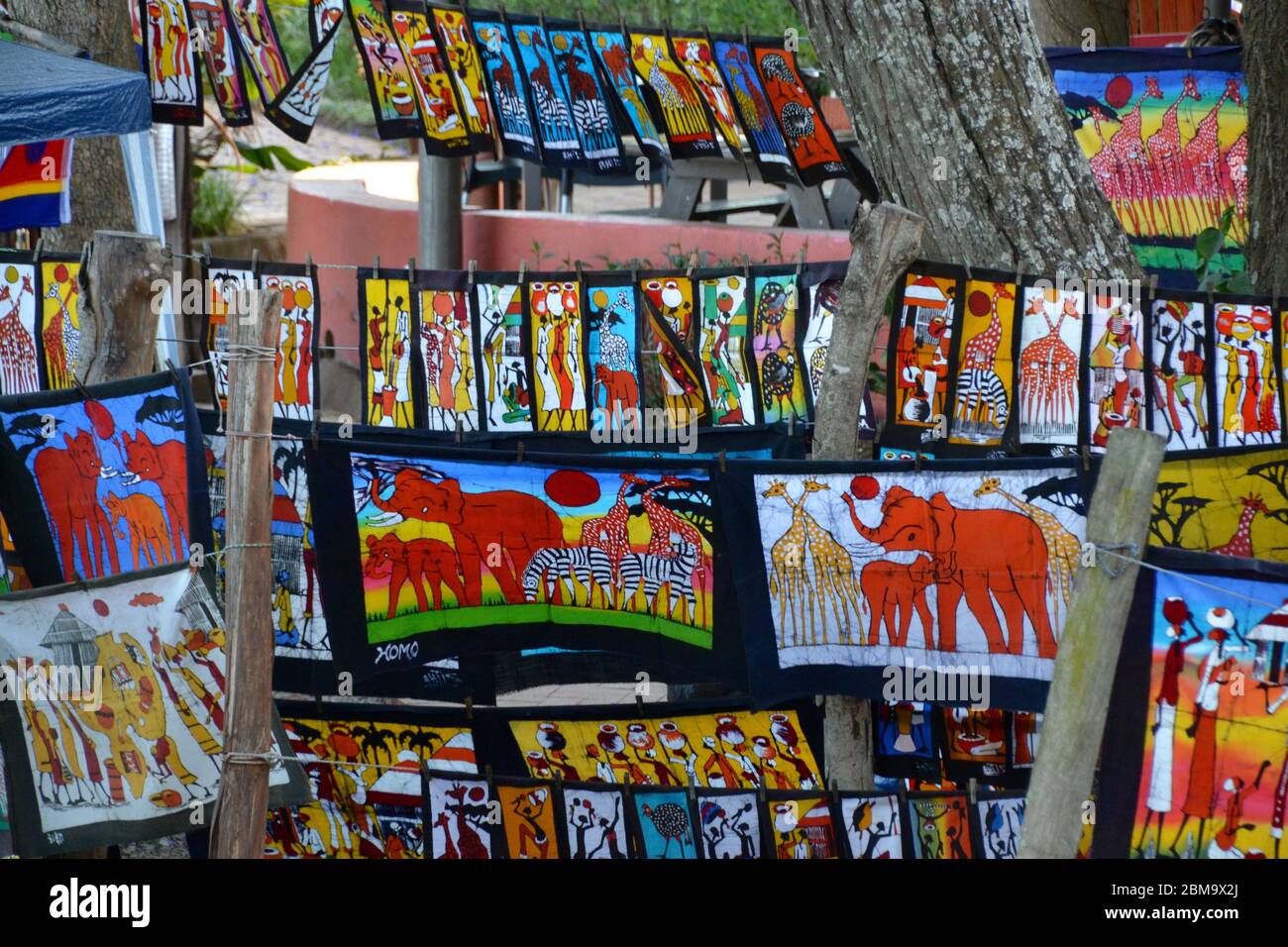 Telas coloridas y grabados en un mercado al aire libre en Eswatini (Swazilandia) con referencias culturales y animales africanos Foto de stock