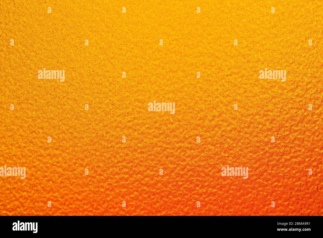 Imagen horizontal. El fondo que tiene sólo un ligero sombreado naranja a un color amarillo. Tiene una superficie áspera. Foto de stock