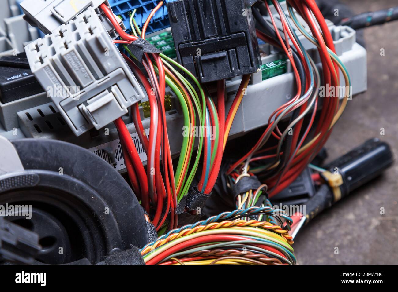 Cables eléctricos de varios colores con conectores en los nodos del vehículo  durante la reparación de la red por parte de un técnico o mecánico en  servicio o taller Fotografía de stock -