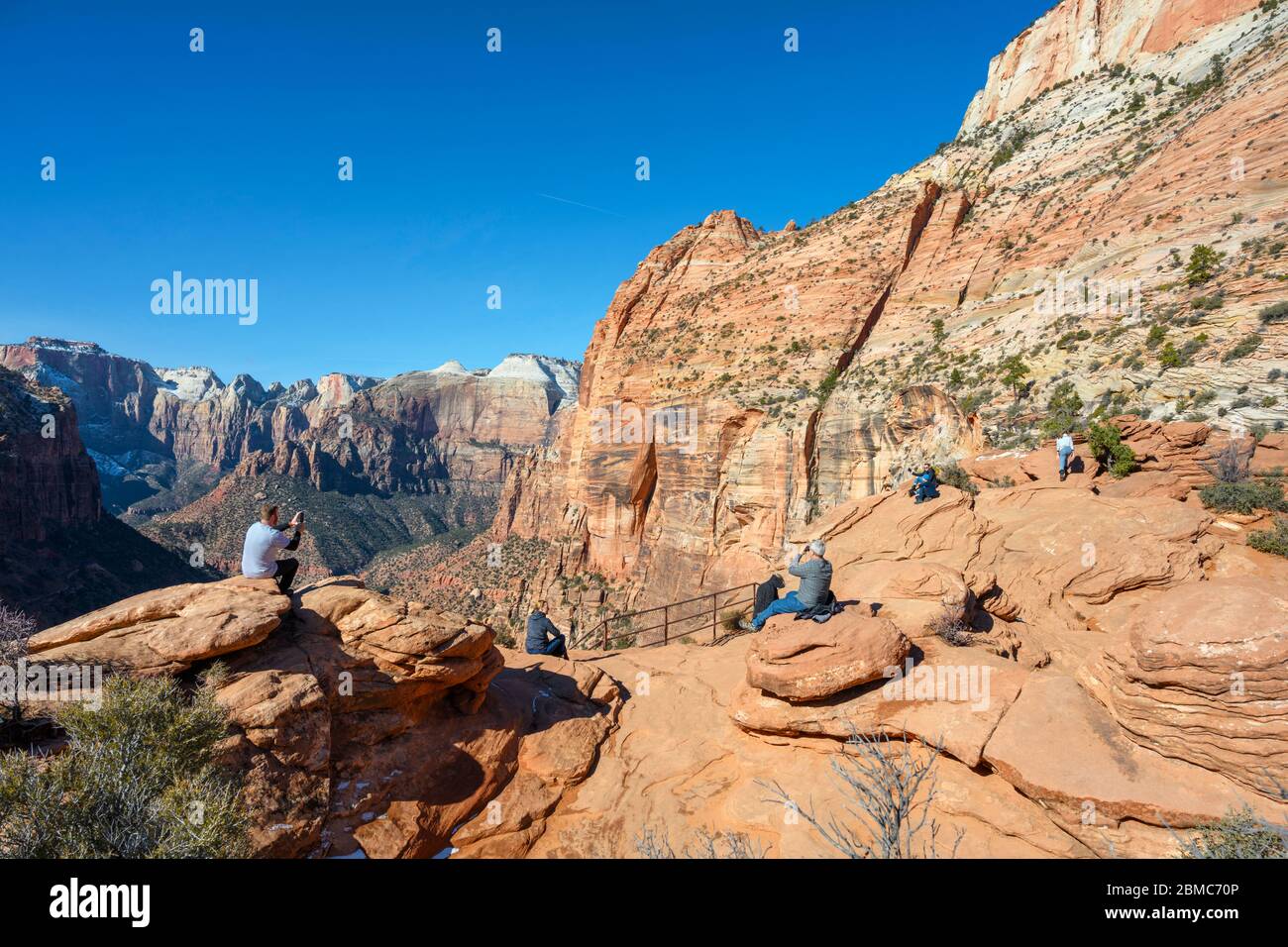 Los senderistas que miran hacia la vista del Cañón Zion desde el mirador del Cañón, el Parque Nacional Zion, Utah, Estados Unidos Foto de stock