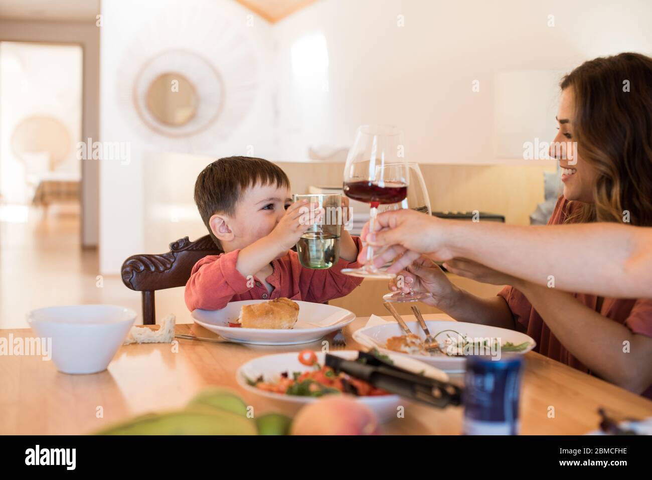 Familia joven con un niño pequeño sentado juntos para el almuerzo Foto de stock