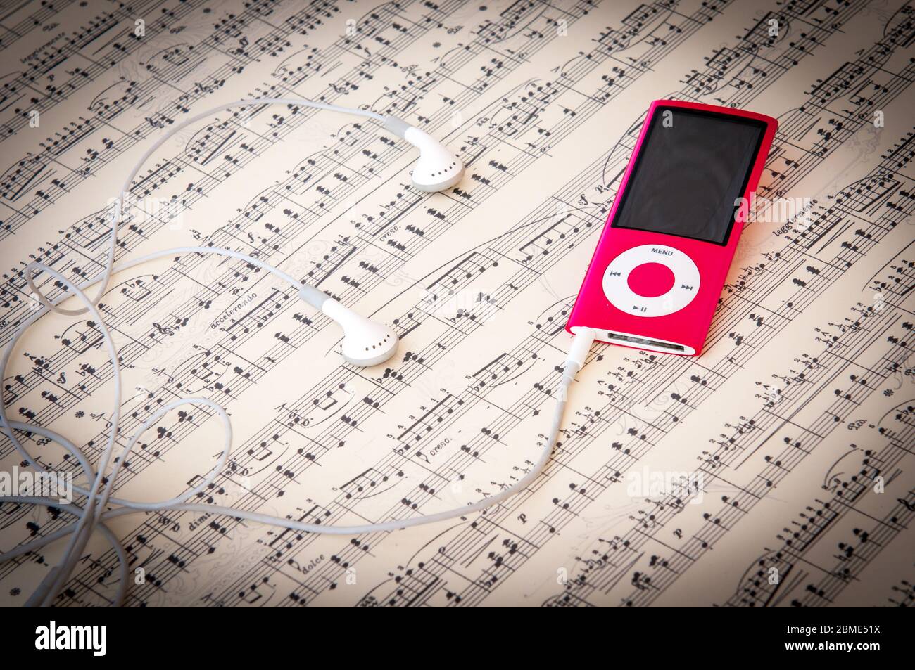 Reproductor de música MP3 rojo y auriculares sobre un fondo de lámina  musical con notas de canción Fotografía de stock - Alamy