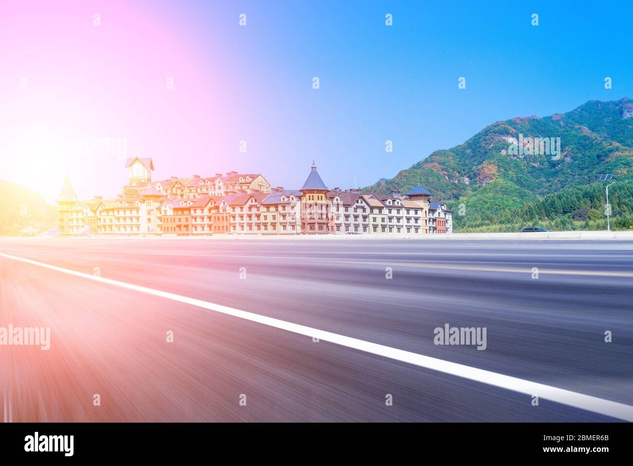 Edificio europeo del castillo y carretera asfaltada bajo el cielo azul de montaña. Foto de stock