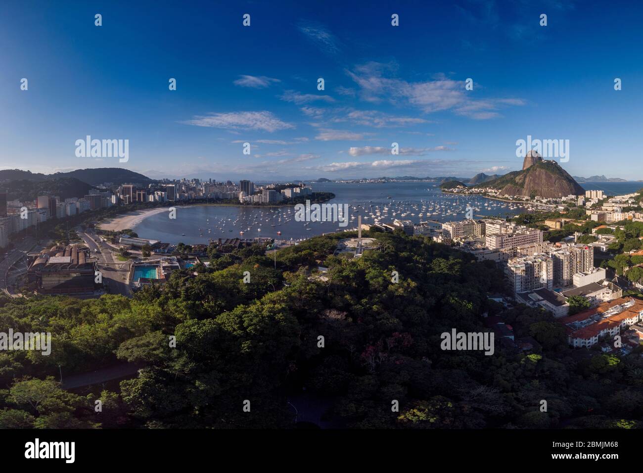 Playa Botafogo y montaña Sugarloaf a ambos lados del puerto de la bahía de Guanabara para los barcos de placer contra un cielo azul con el parque de la colina pasmado y vistas Foto de stock