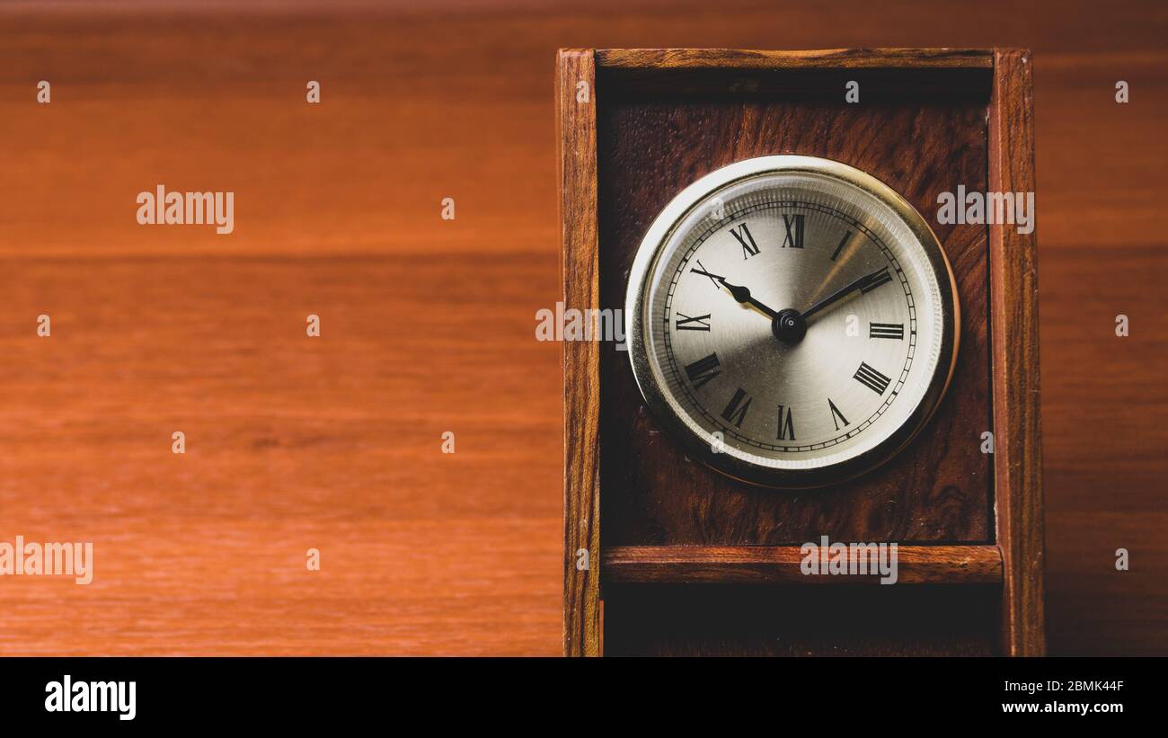 Reloj retro de madera. Reloj clásico cuadrado con esfera redonda. Mesa de madera. Espacio para copiar Foto de stock