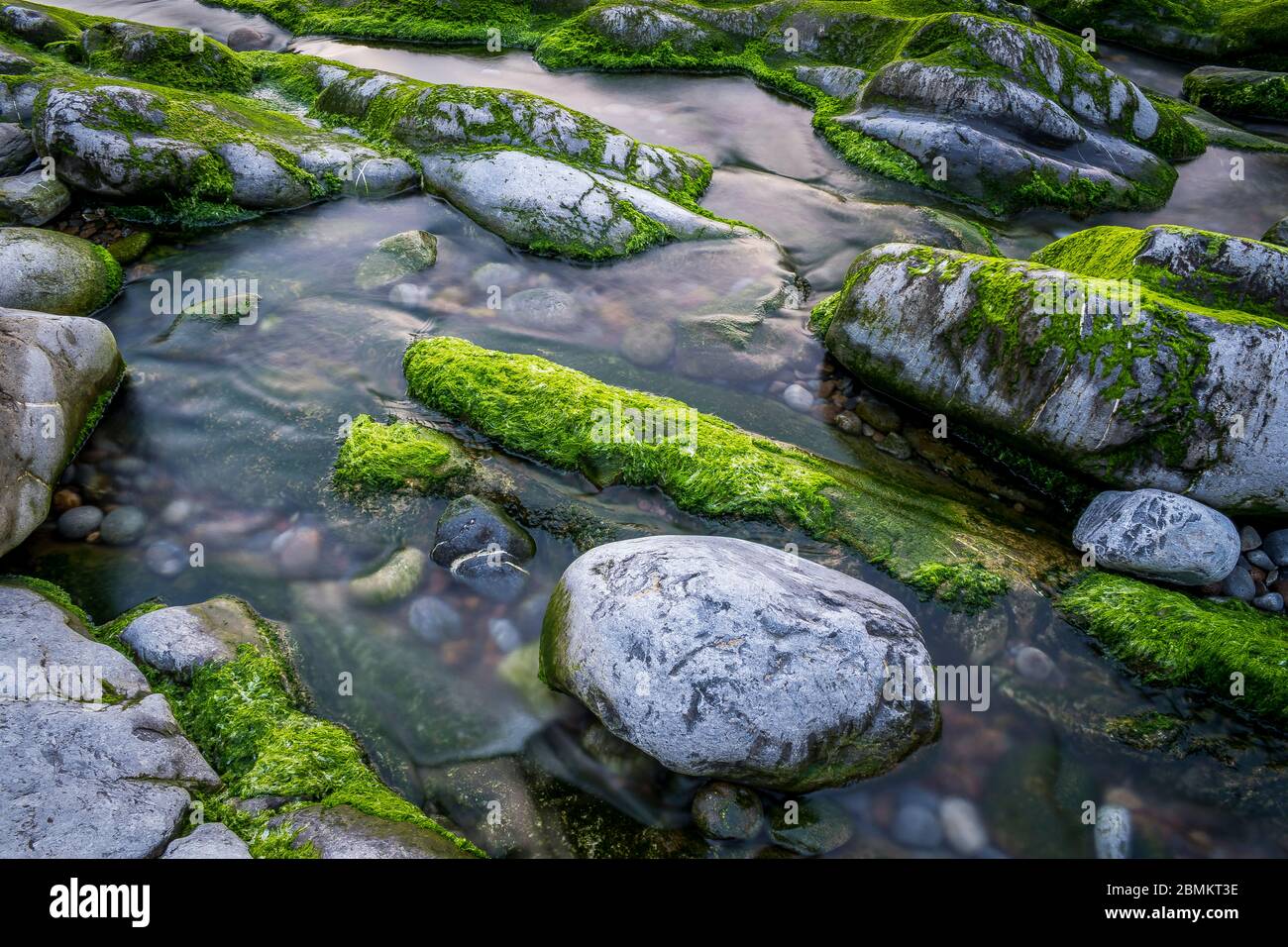 Exposición larga de un río con rocas y musgo Foto de stock