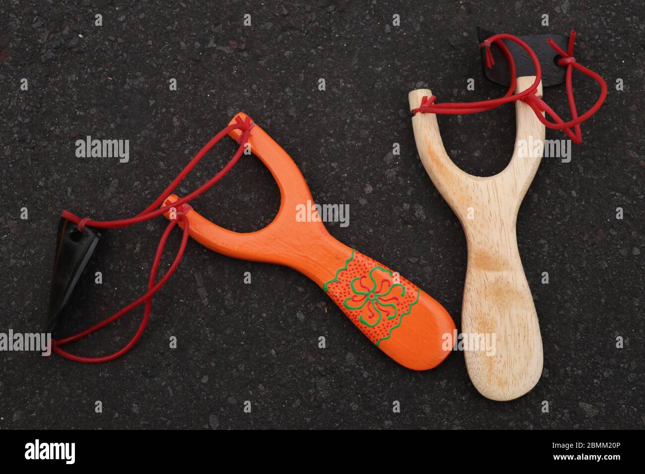 Pareja de simple madera de bala aislada. Mango de madera naranja y natural con dos bandas de goma rojas adheridas a una tira de cuero negro utilizada para poner t Fotografía de Pareja de simple madera de bala aislada. Mango de madera naranja y natural con dos bandas de goma rojas adheridas a una tira de cuero negro utilizada para poner t Fotografía de