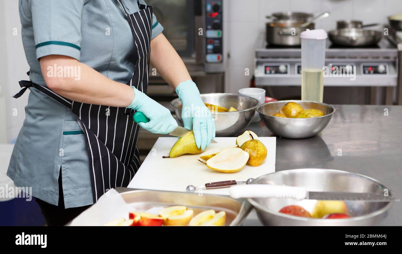 Mujer irreconocible cortando pera en la mesa de la cocina Foto de stock