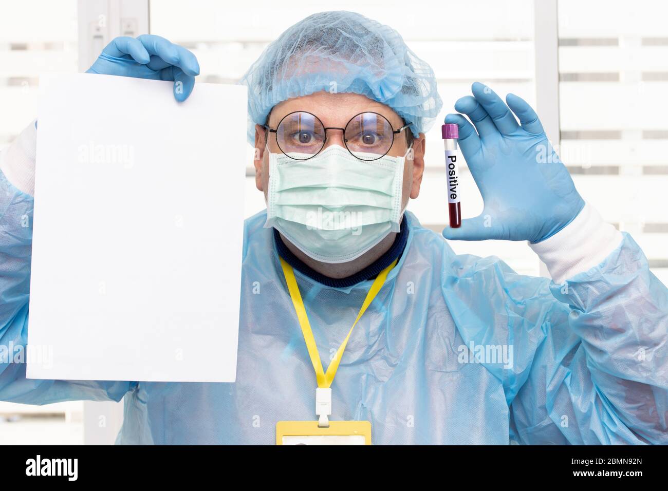 Médico en traje protector sosteniendo un papel blanco vacío y tubo con resultados positivos de análisis de sangre. El personal médico muestra un cartel en blanco con la prueba positiva o. Foto de stock