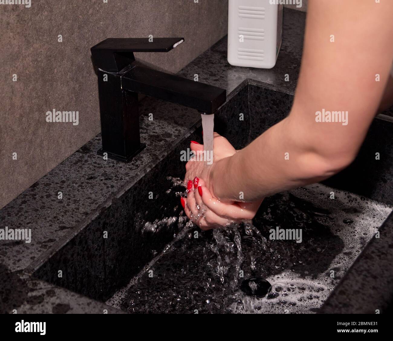Mujer lavándose las manos, enjuagándose las manos bajo agua corriente limpia. Higiene para dejar de propagar el virus. Foto de stock