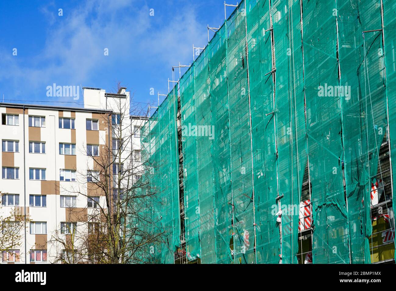 red de seguridad verde en andamios en la fachada de una casa de apartamentos Foto de stock