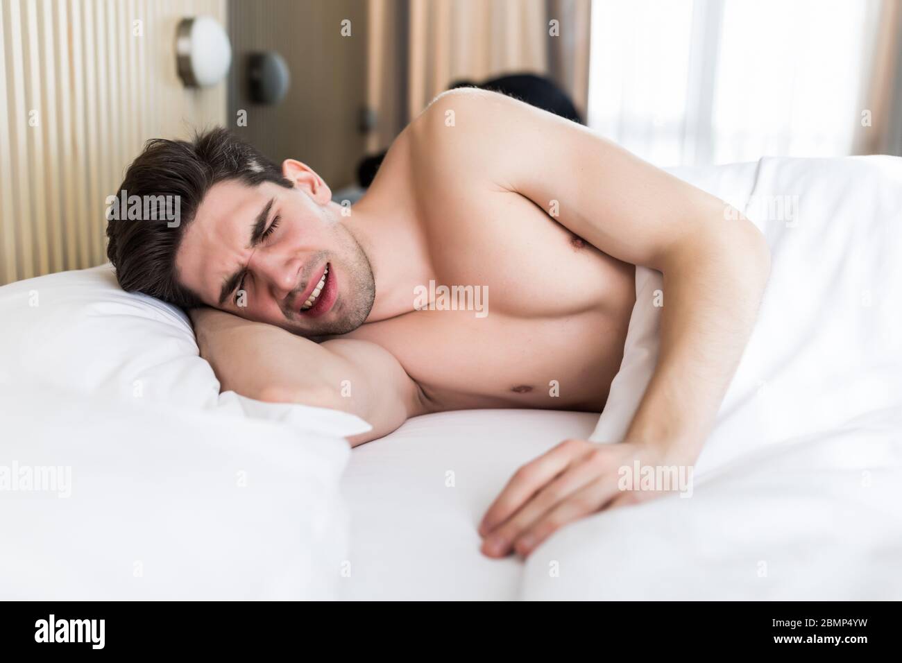 Un hombre joven guapo durmiendo sobre una almohada en la cama Fotografía de  stock - Alamy
