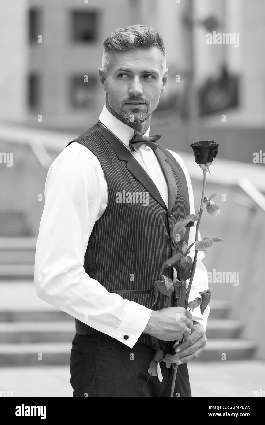 Caballero real celebración aumentó en mano. ser mi Valentín. Día de las  mujeres concepto. Hombre con rosa flor. Hombre de vestimenta formal la  celebración de rosa roja. Poner en una pajarita. mens