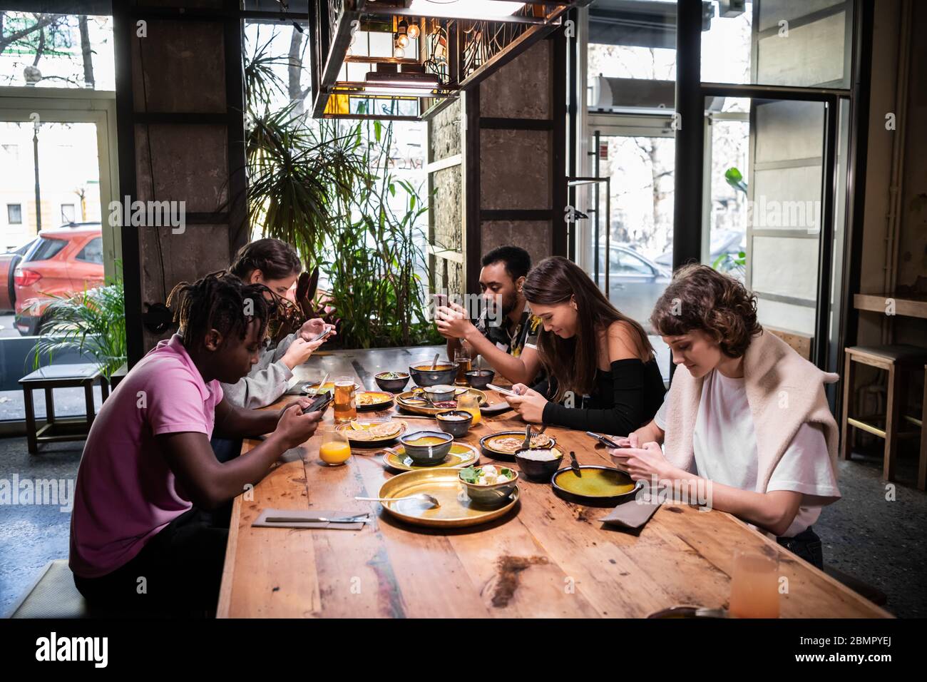 Un grupo multiétnico de estudiantes que comen en un café moderno con fr Foto de stock