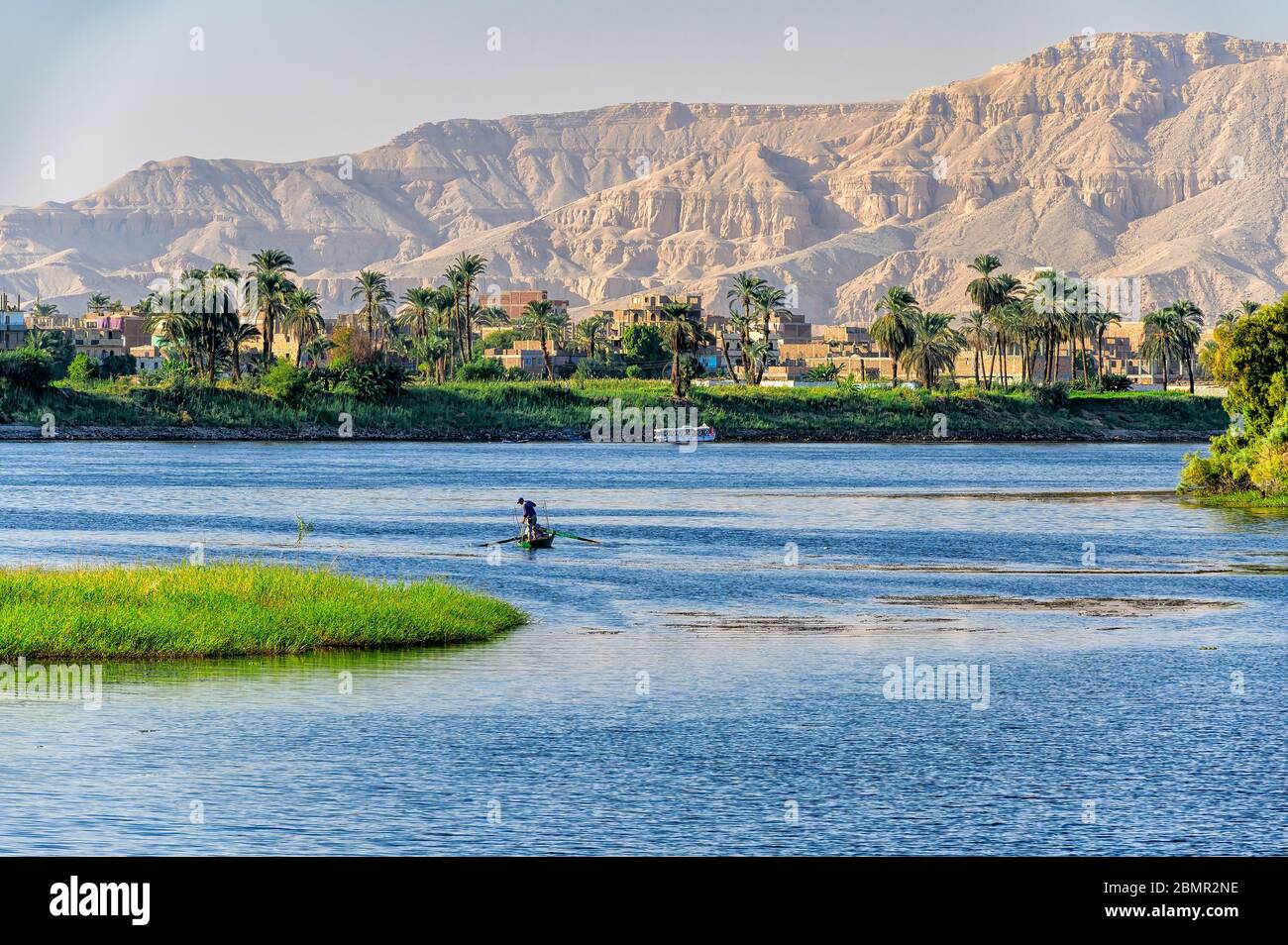 Pescador en el río Nilo transporta en su captura con las montañas de la Ribera Occidental del Nilo en el fondo Foto de stock
